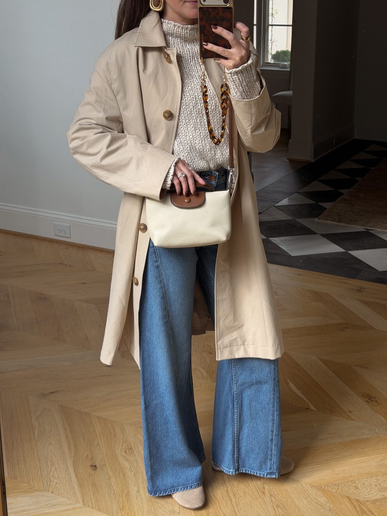 long tan trench coat with a tank sweater and flared jeans for fall 2026